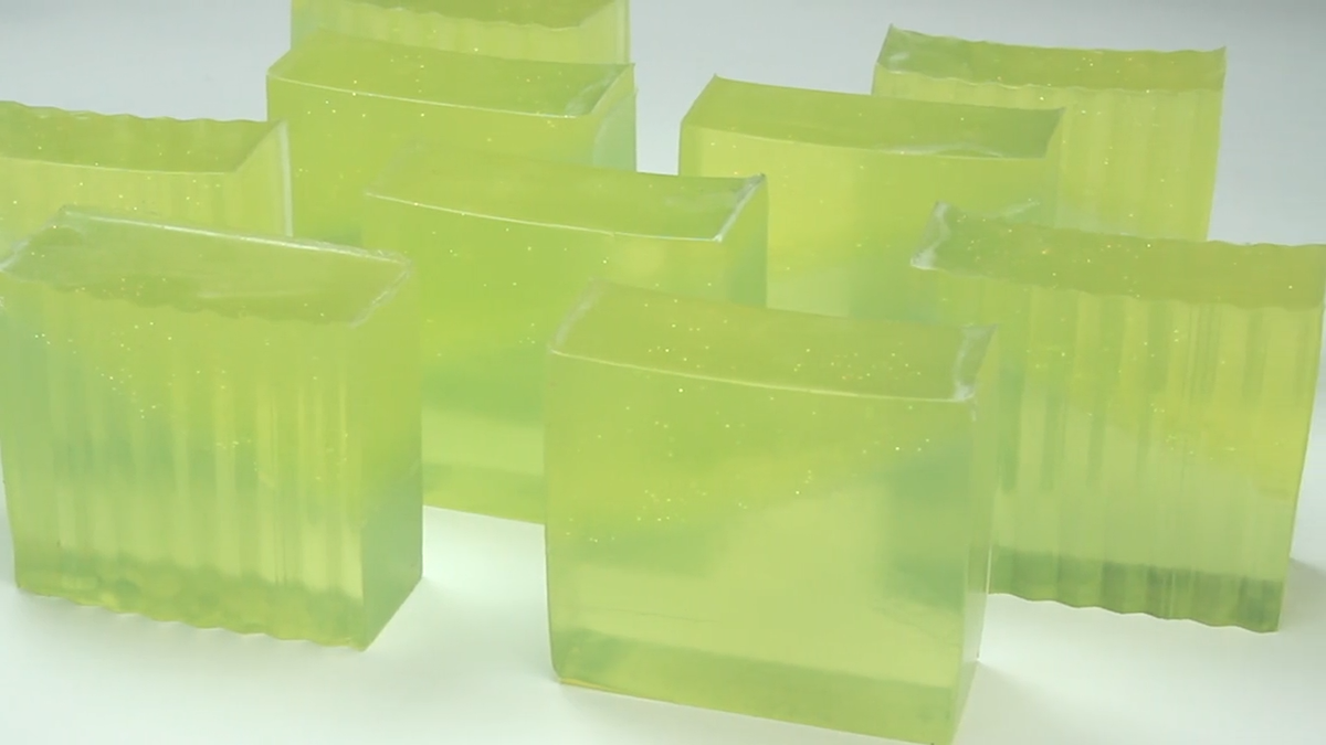 Several translucent lime-green citrus soap bars with ridged sides arranged on a white surface