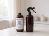 Amber Lone Star VersaMist Room Spray Base bottle beside an amber spray bottle with black trigger sprayer on a counter