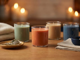 Four soy candles in clear glass tumblers in sage, rust, tan and blue, with sage sprigs and matches