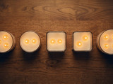 Overhead row of five lit multi-wick candles in round and square jars with two to four flames each
