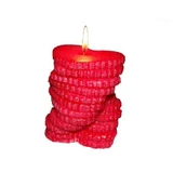 Lit red pillar candle of stacked heart-shaped wax layers on a white background