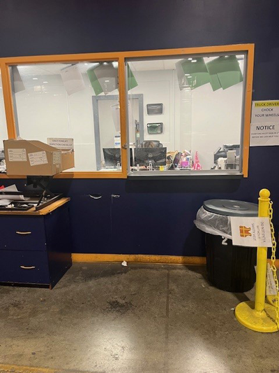 Shipping office pickup window with a counter, navy cabinets, and a yellow bollard sign