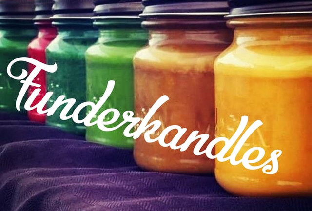 A row of green, red, and orange candle jars on a market table with Funderkandles written in script across them