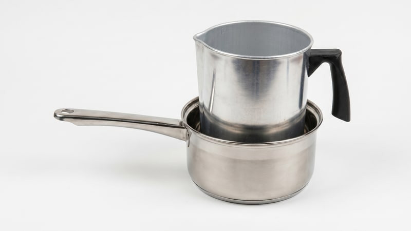 Aluminum pouring pitcher set inside a stainless saucepan forming a double boiler
