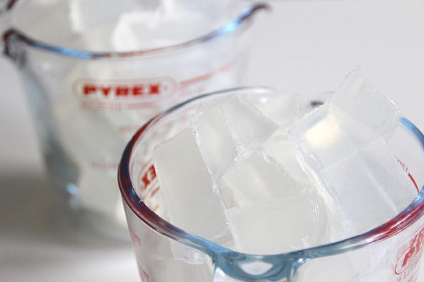 Two Pyrex glass measuring cups filled with clear cubed soap base