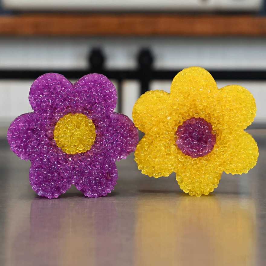 Purple and yellow flower-shaped freshies with yellow centers standing on a kitchen counter