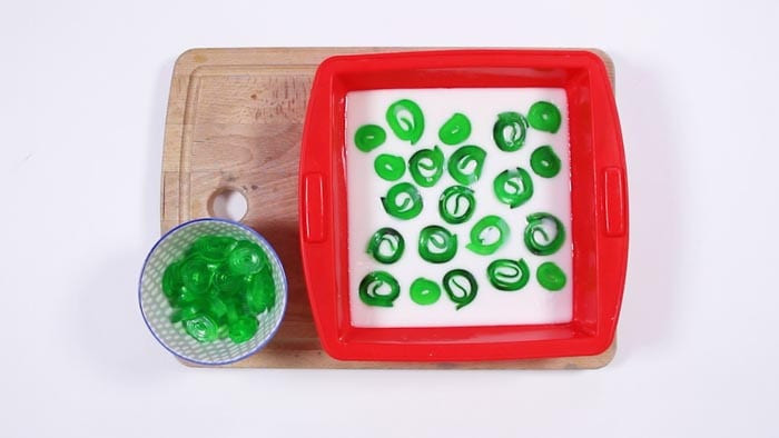 Green soap spirals placed on white soap in a red square mold, extra spirals in a bowl