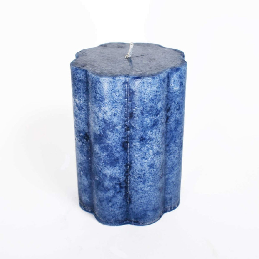Finished mottled deep-blue fluted pillar candle with centered wick on white background