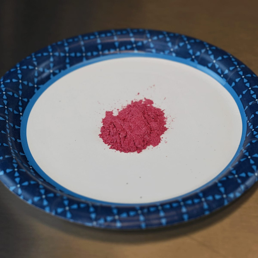 A mound of pink mica powder on a white paper plate